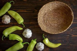 Green hot chili peppers and garlic on wooden background photo
