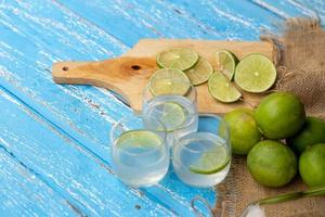 Jugo de lima y limón sobre una mesa de madera azul foto