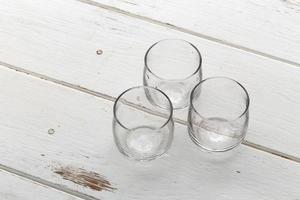 Tres vasos vacíos en una mesa de madera blanca