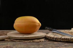 Ripe papaya fruit cut into pieces on wooden background photo