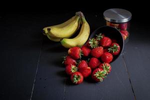 Ripe red strawberries on black wooden table photo