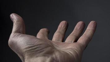 Man's Hand Begs For Something On A Dark Background photo