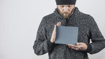 hombre barbudo sostiene en sus manos un cartel de cartón gris en blanco foto