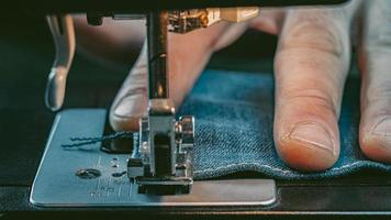 hombre mano coser denim en una máquina de coser foto