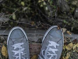 Zapatillas grises en las piernas de un hombre con un telón de fondo de follaje de otoño foto