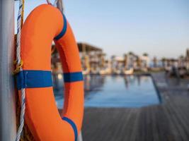 Orange lifebuoy near public swimming pool On a blurred background, a swimming pool is visible photo