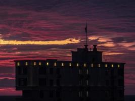 SILHOUETTE OF A BUILDING WITH A FLAG ON BACKGROUND OF A BEAUTIFUL SUNRISE WITH CLOUDS photo