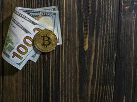 Golden Bitcoin on US dollars. Digital currency close-up on a wooden background.Real coins of bitcoin on banknotes of one hundred dollars photo