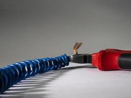 Close up of red pliers and blue twisted wire on white background.Pliers cutting cable photo