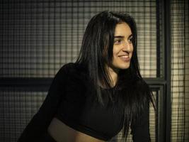 portrait of brunette girl in black top looking in the mirror in the gym against the background of the lattice photo