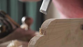 carpenter cuts off excess on a wooden board with a flat chisel