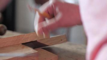 un falegname segna una tavola di legno con una squadra di prova video