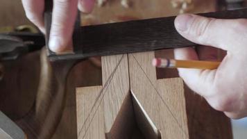 un carpintero marca una tabla de madera con un cuadrado de prueba