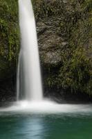 una pequeña cascada en las montañas de los Cárpatos que fluye de un barranco tallado en piedra y cubierto de musgo