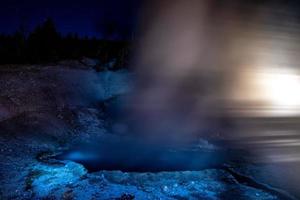 yellowstone geysers erupting at night illuminated by light photo