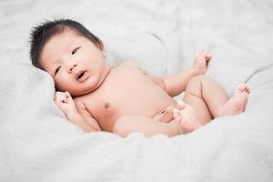 Newborn infant baby boy lying on a white blanket photo