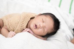 Happy cute adorable Asian baby boy with black hair lying a white blanket photo