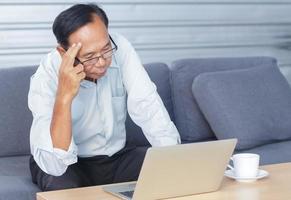 Asian senior man feeling unwell due to illness and stress photo