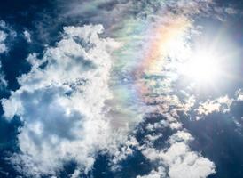 blue sky white clouds sun and rainbow photo