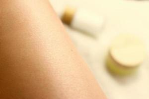 Epilation, leg skin close up with bottles of cream photo