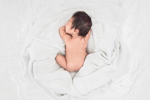 Baby sleeps on soft white blanket, Top view photo