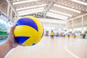 La mano izquierda sostiene una pelota de voleibol para el juego de voleibol. foto