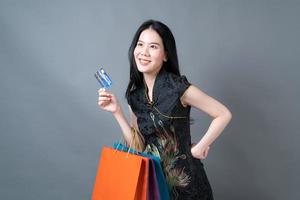 Mujer asiática vistiendo traje tradicional chino con bolsa de compras y tarjeta de crédito foto