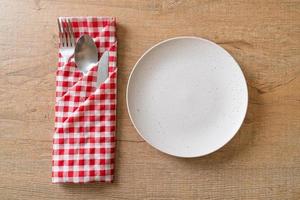 Plato vacío o plato con cuchillo, tenedor y cuchara sobre fondo de baldosas de madera foto