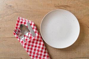 Empty plate or dish with knife, fork, and spoon on wood tile background photo