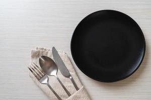 Empty plate or dish with knife, fork, and spoon on wood tile background photo