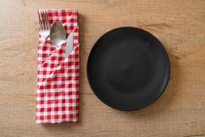 Empty plate or dish with knife, fork, and spoon on wood tile background photo