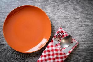 Empty plate or dish with knife, fork, and spoon on wood tile background photo