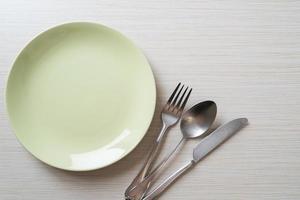 Plato vacío o plato con cuchillo, tenedor y cuchara sobre fondo de baldosas de madera foto
