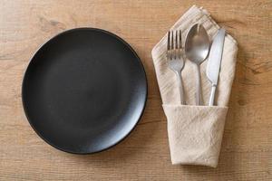 Empty plate or dish with knife, fork, and spoon on wood tile background photo