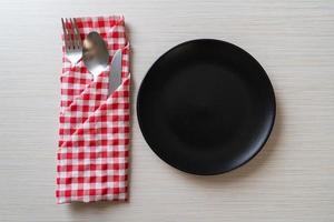 Empty plate or dish with knife, fork, and spoon on wood tile background photo