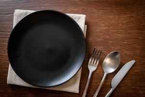 Empty plate or dish with knife, fork, and spoon on wood tile background photo