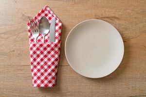 Empty plate or dish with knife, fork, and spoon on wood tile background photo