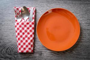 Empty plate or dish with knife, fork, and spoon on wood tile background photo