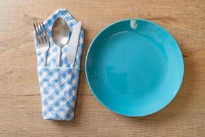 Empty plate or dish with knife, fork, and spoon on wood tile background photo