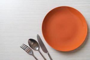 Empty plate or dish with knife, fork, and spoon on wood tile background photo