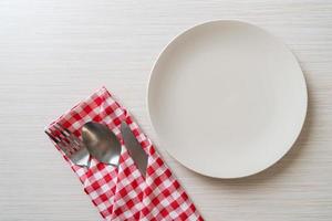 Empty plate or dish with knife, fork, and spoon on wood tile background photo