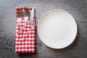 Empty plate or dish with knife, fork, and spoon on wood tile background photo