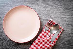 Empty plate or dish with knife, fork, and spoon on wood tile background photo