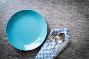 Empty plate or dish with knife, fork, and spoon on wood tile background photo