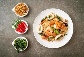 fideos chinos salteados con albahaca, chile, camarones y calamares - estilo de comida asiática foto