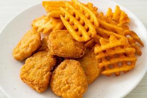 Fried chicken nuggets with fried potatoes on plate photo