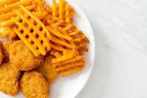 Fried chicken nuggets with fried potatoes on plate photo