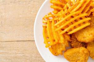 Fried chicken nuggets with fried potatoes on plate photo