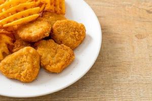 Fried chicken nuggets with fried potatoes on plate photo