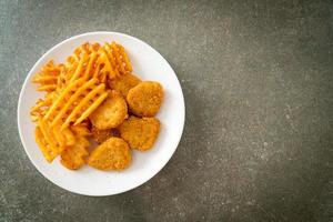 Fried chicken nuggets with fried potatoes on plate photo